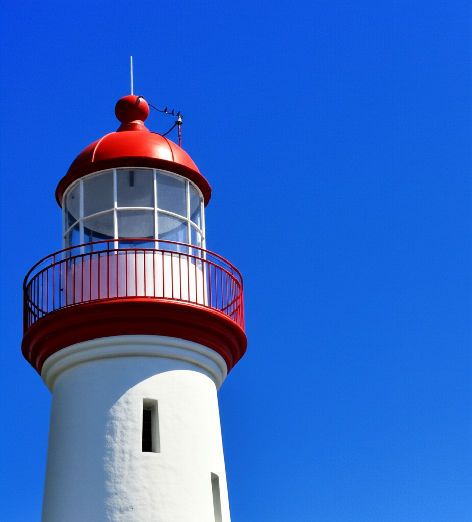 Close-up da estrutura branca e cilíndrica do Farol de Itacaré, com sua cúpula vermelha e o céu azul vibrante ao fundo, destacando a simplicidade e funcionalidade de sua arquitetura.
