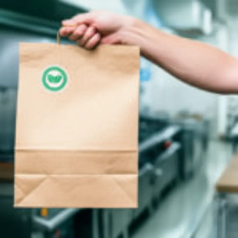 Saco Kraft sustentável sendo segurado em uma cozinha moderna e limpa, destacando sua textura natural e selo ecológico.